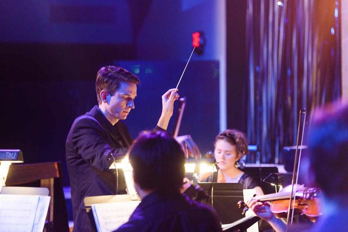 A conductor leads a student orchestra
