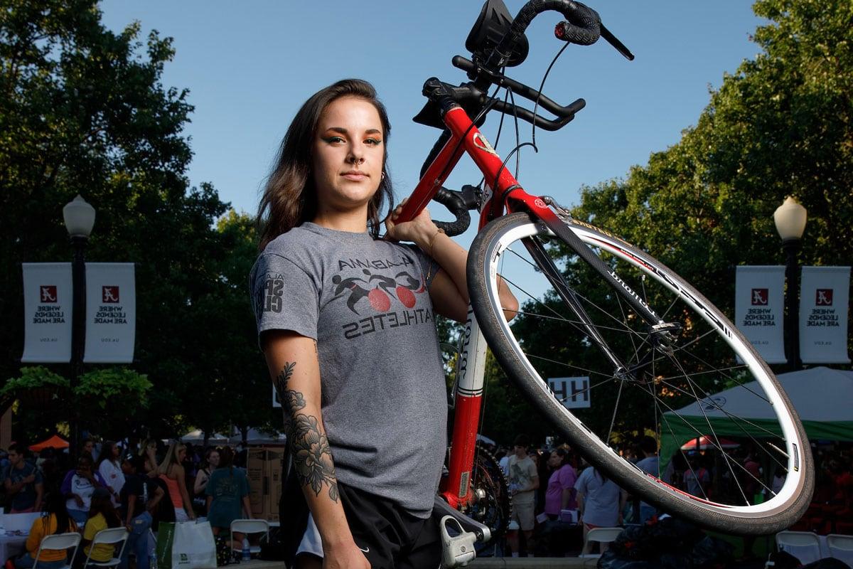 A student representing the spin club holds her bicycle